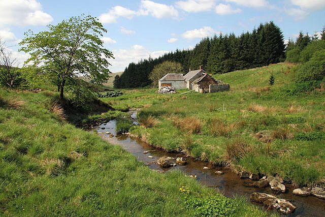 A rural landscape with a stream, a tree, and a house on a hill.