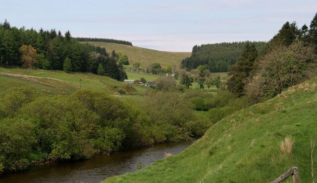 A river flowing through a green valley with hills and trees.