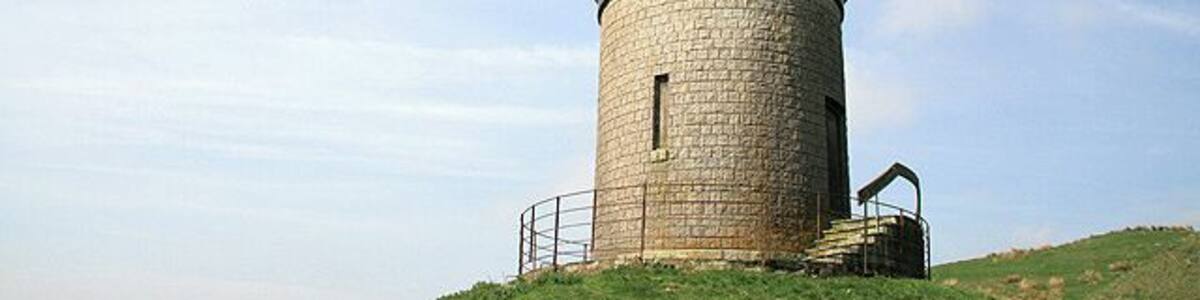 Monument on Tanlawhill Rig This tower, overlooking the Black Esk river and Castle O'er Forest, is marked on the O.S. map as a monument. It is cylindrical in shape and constructed of granite blocks with a splayed 360 degree glazed viewing screen, topped with a conical copper roof. There is a tiled walkway around the tower enclosed in a metal fence. The external wall contains a timber door and 3 narrow boarded-up windows.