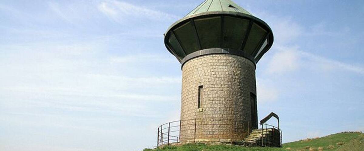Monument on Tanlawhill Rig This tower, overlooking the Black Esk river and Castle O'er Forest, is marked on the O.S. map as a monument. It is cylindrical in shape and constructed of granite blocks with a splayed 360 degree glazed viewing screen, topped with a conical copper roof. There is a tiled walkway around the tower enclosed in a metal fence. The external wall contains a timber door and 3 narrow boarded-up windows.