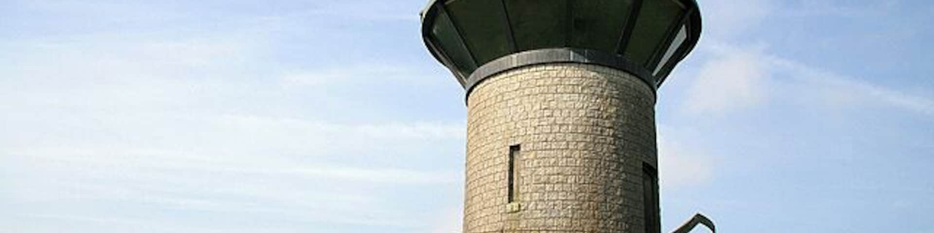 Monument on Tanlawhill Rig This tower, overlooking the Black Esk river and Castle O'er Forest, is marked on the O.S. map as a monument. It is cylindrical in shape and constructed of granite blocks with a splayed 360 degree glazed viewing screen, topped with a conical copper roof. There is a tiled walkway around the tower enclosed in a metal fence. The external wall contains a timber door and 3 narrow boarded-up windows.