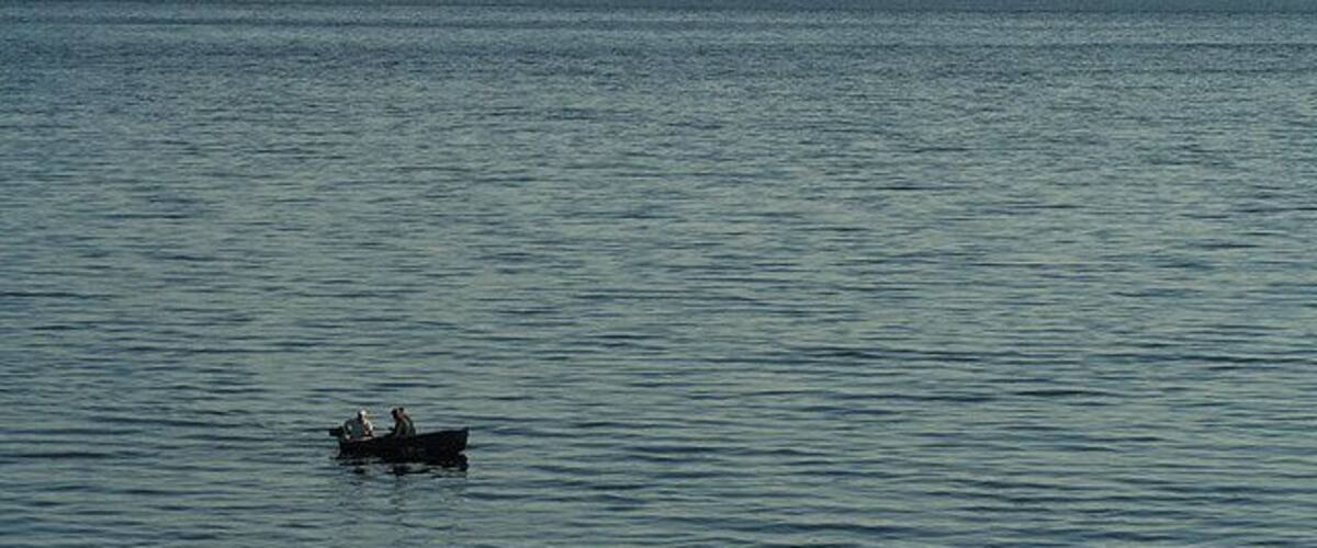 A calm lake with a small boat carrying two people.