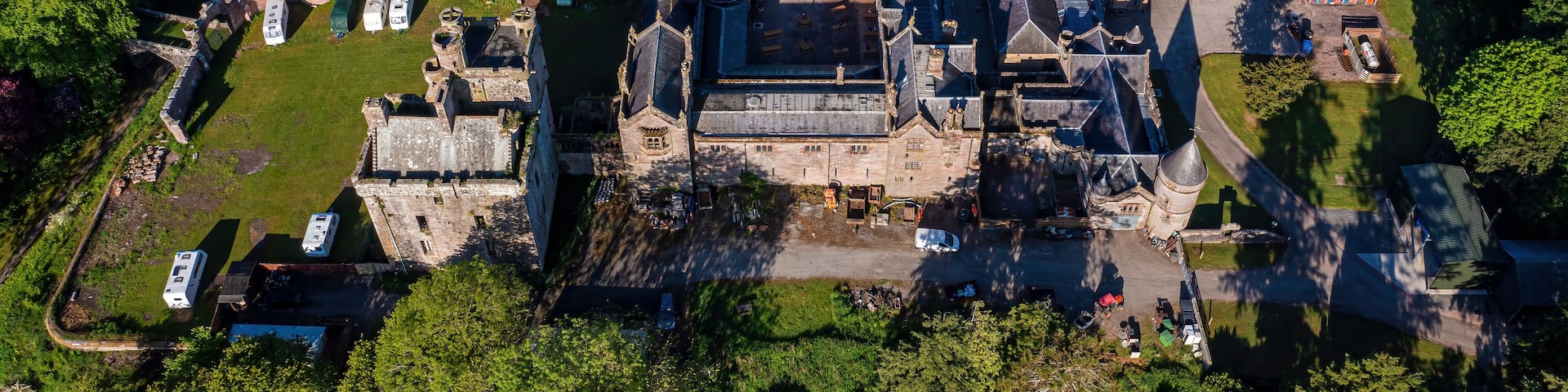 An aerial view of a historic castle surrounded by a park with camping facilities.
