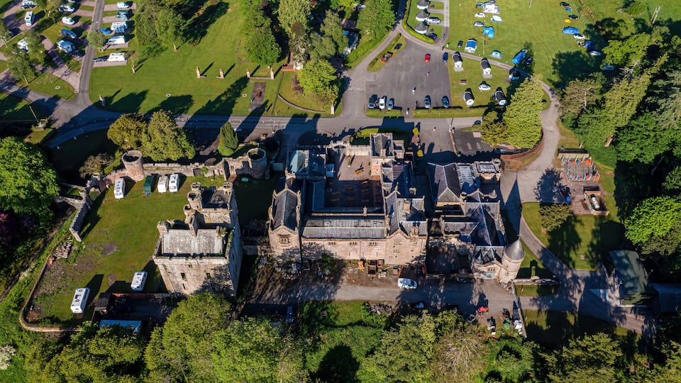 An aerial view of a historic castle surrounded by a park with camping facilities.