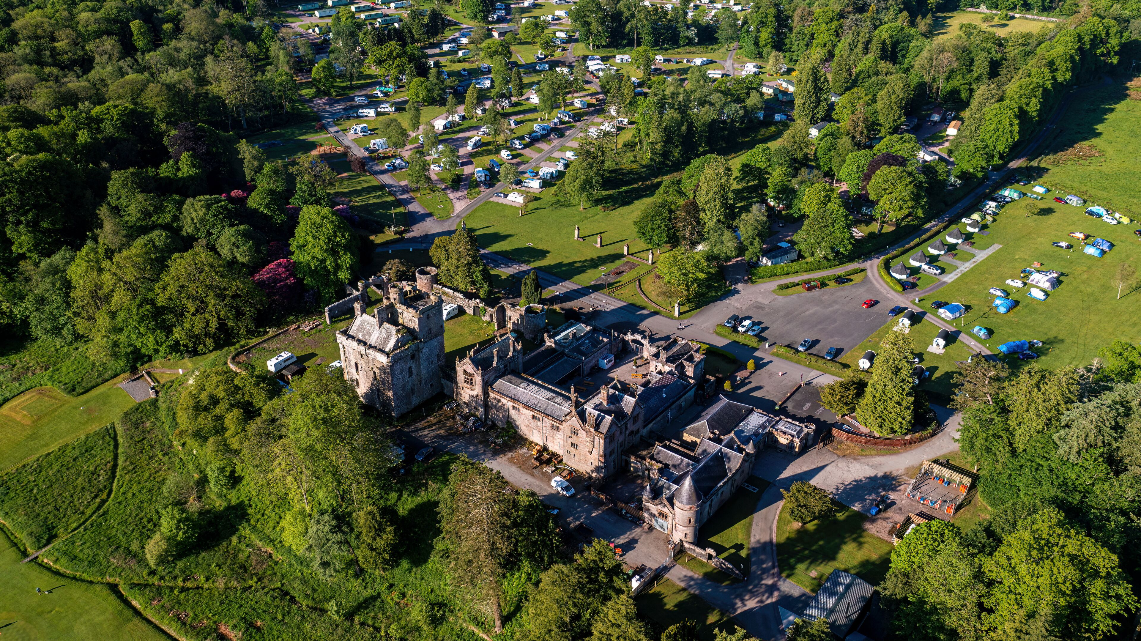 An aerial view of a castle surrounded by a camping area with RVs and tents.