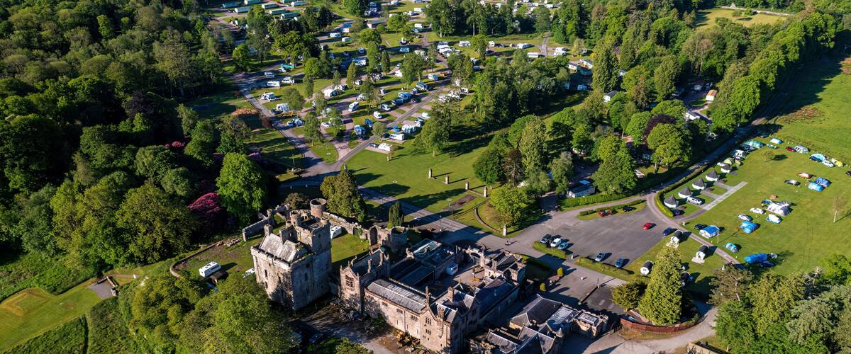 An aerial view of a castle surrounded by a camping area with RVs and tents.