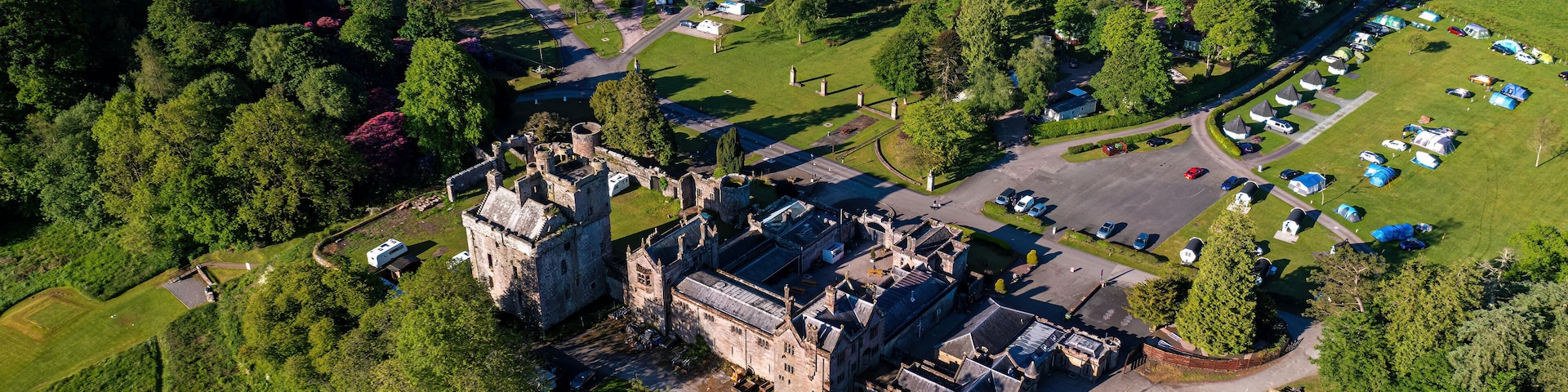 An aerial view of a castle surrounded by a camping area with RVs and tents.