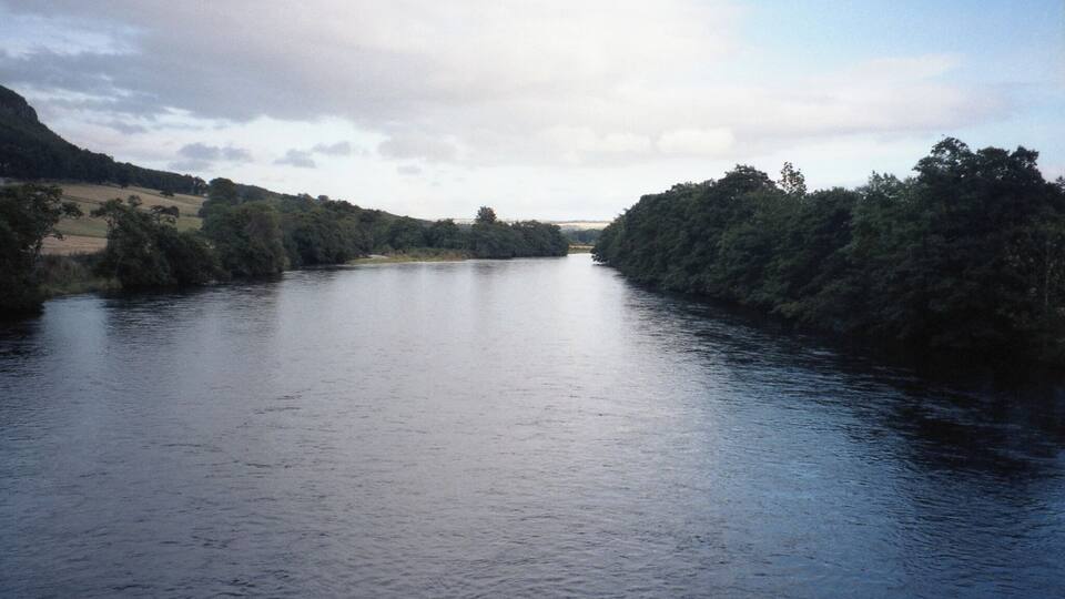 A river flanked by dense forests and hills.