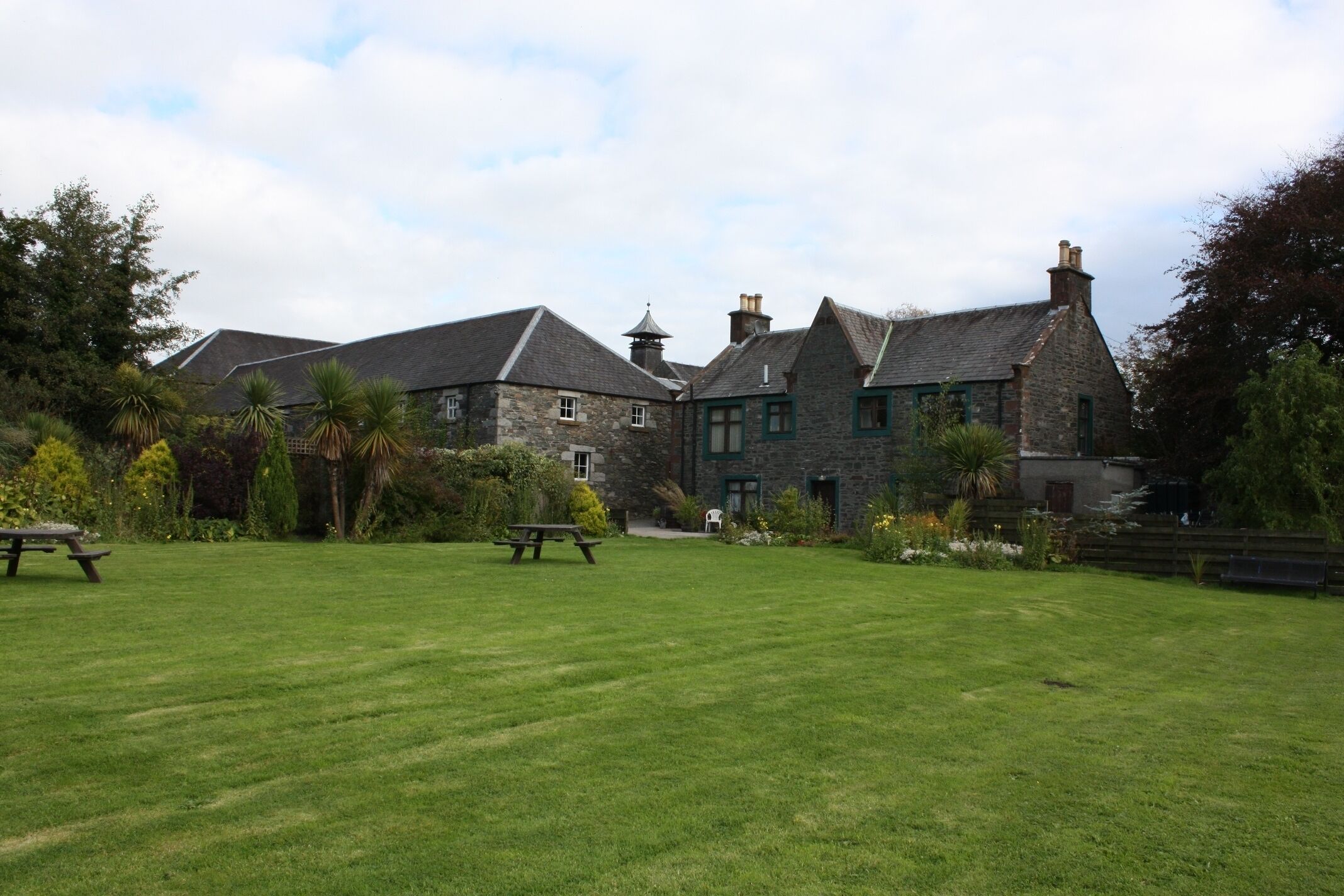 A large stone building with a grassy lawn and picnic tables.
