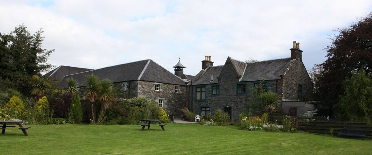 A large stone building with a grassy lawn and picnic tables.