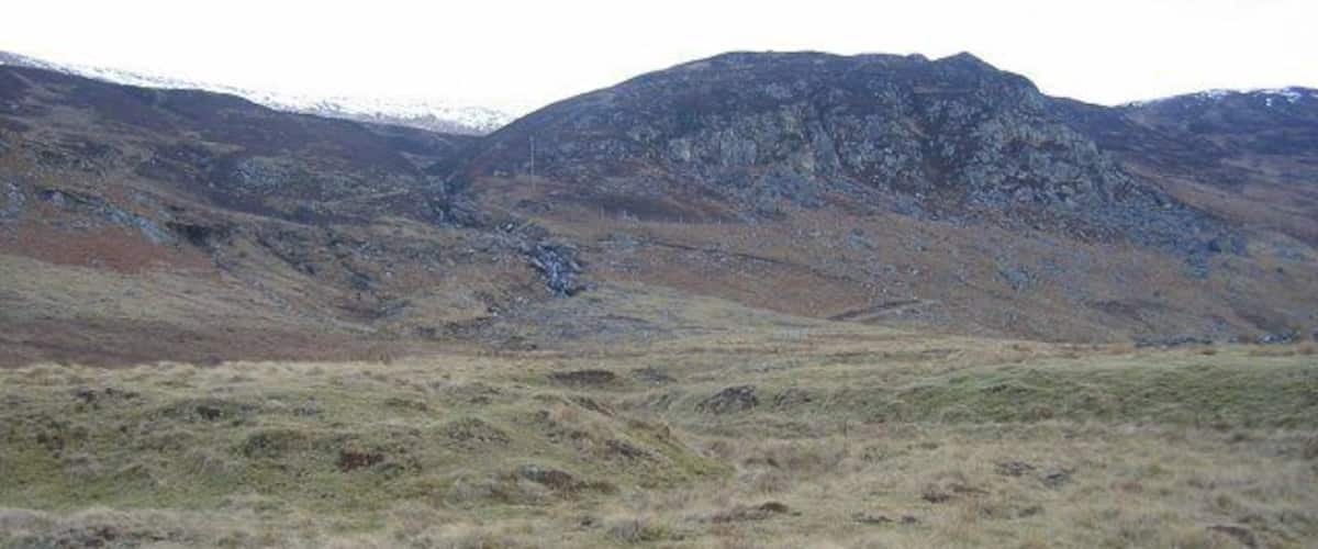 A mountainous landscape with grassy fields and rocky terrain.