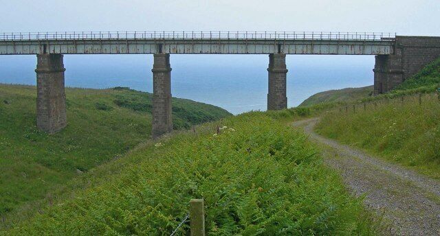 Masonry piered railway bridge over burn north of Muchalls, Kindardineshire The North Sea is in the background. Service road at right is used for water works access.