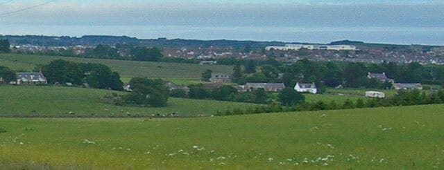 Undulating fields with urban development beyond The urban development in the background is associated with the A90 dual carriageway.