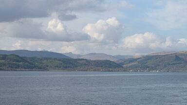 A lake with mountains in the background and a cloudy sky.