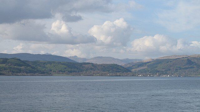 A lake with mountains in the background and a cloudy sky.