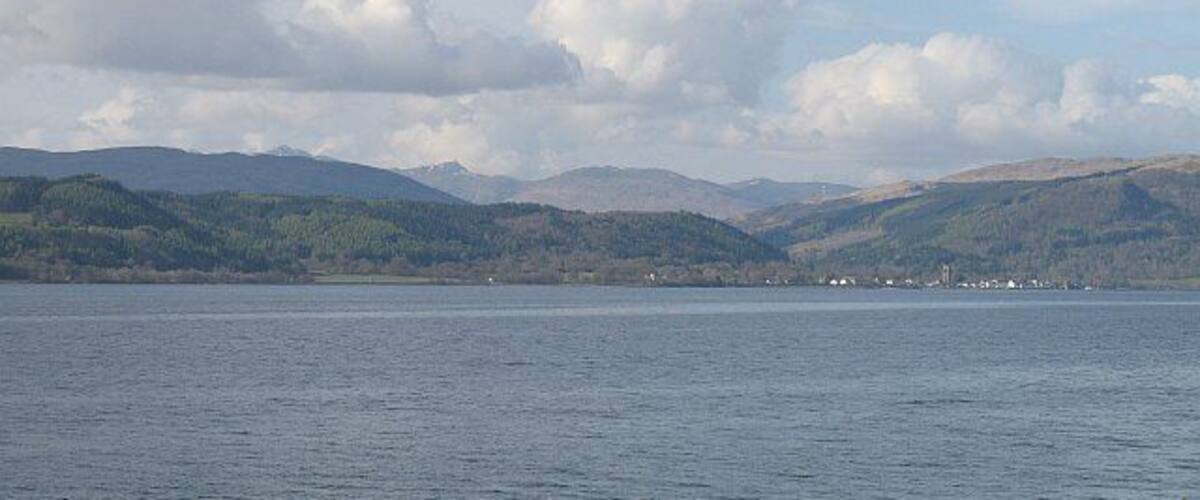 A lake with mountains in the background and a cloudy sky.