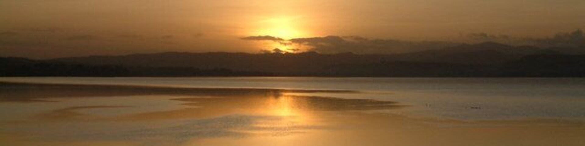 Atardecer sobre un lago tranquilo, con el reflejo nítido del sol.