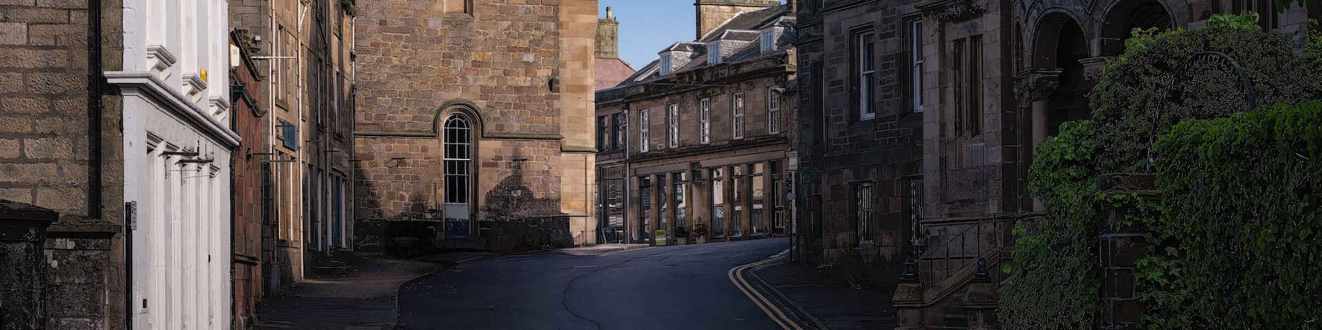 2023-06-04 MAIN STREET THROUGH CITY OF TAIN WITH OLD STONE BUILDINGS WITH SPIRLAS AND A CLOCK IN SCOTLAND