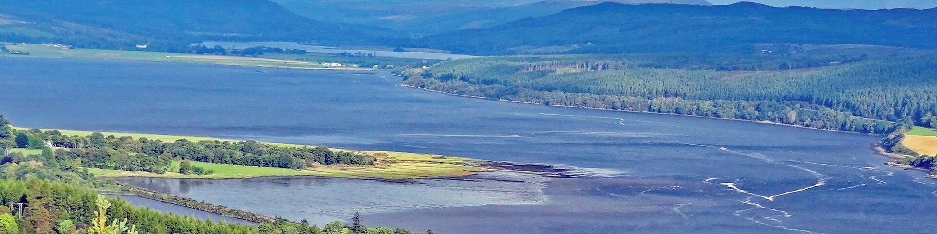 view from the B9176 over Dornoch Firth with Loch Migdale in the far side and a wind farm on the hilltops in the background