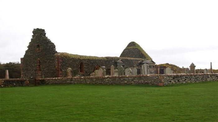 An old stone building with a grassy field in front.