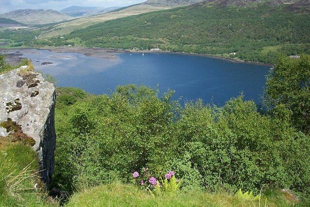 A lake surrounded by hills and greenery.