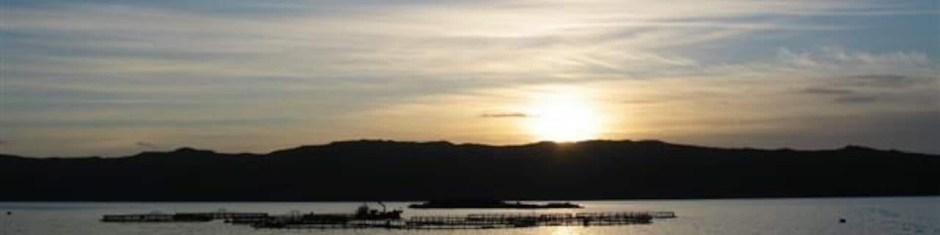 Sunset over fish farm cages.