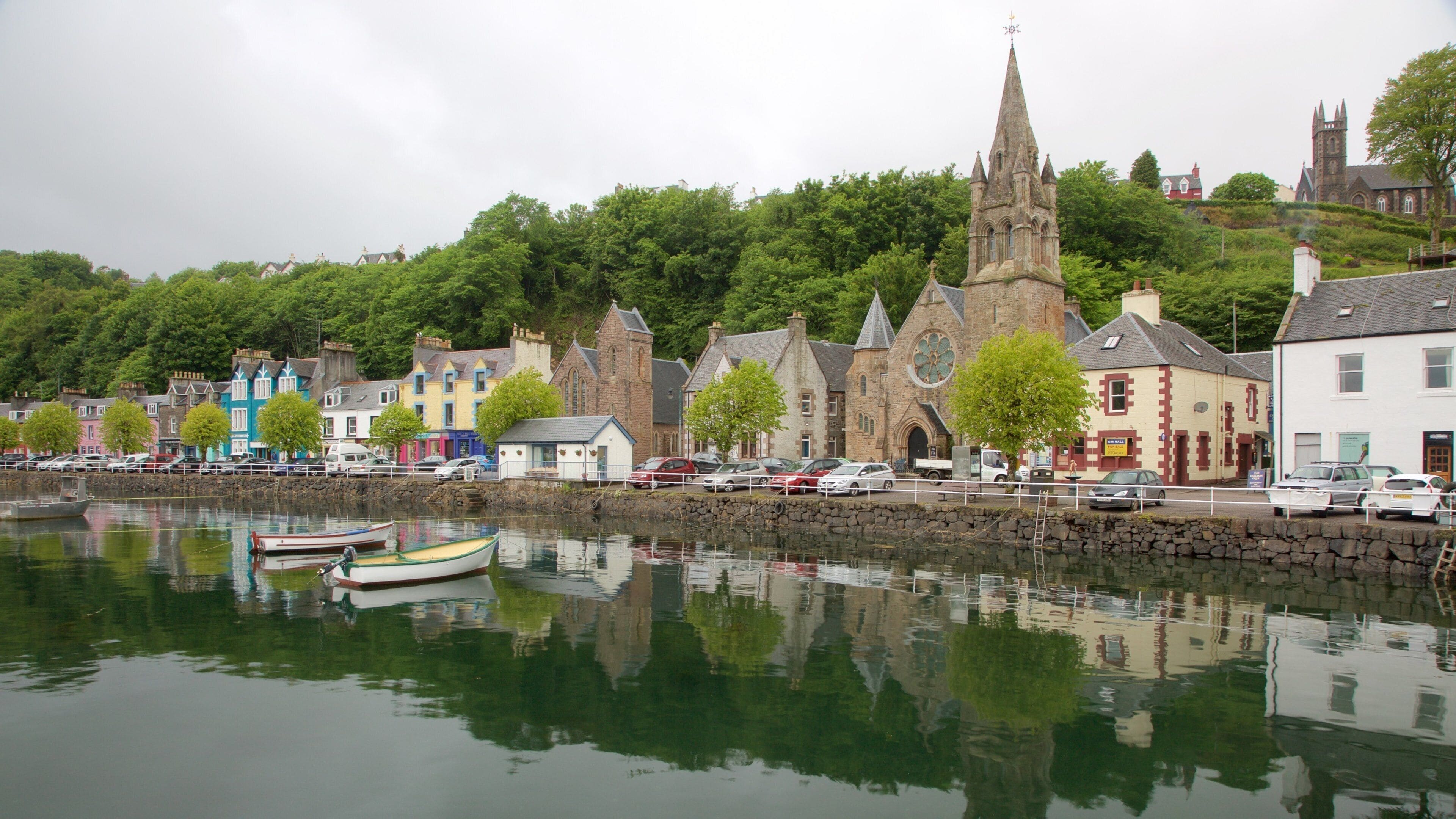 A calm harbor with boats, colorful buildings, and a church with a tall spire.