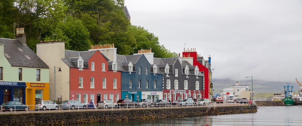 A waterfront with colorful buildings, a stone wall, and a fishing boat.