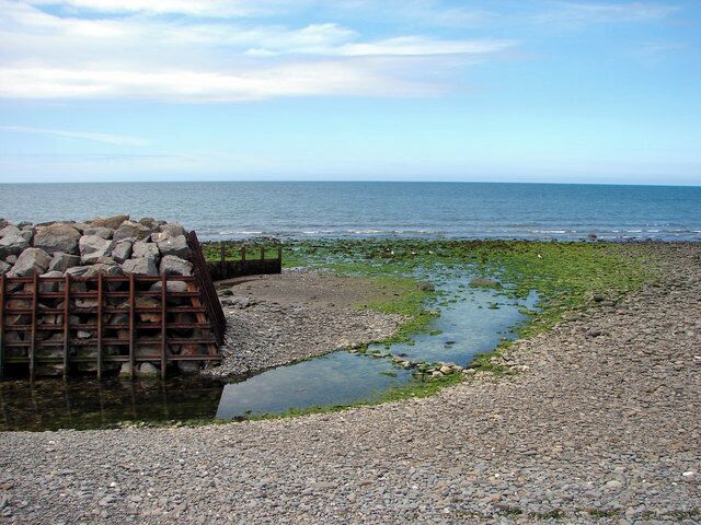 A rocky shoreline with a pile of rocks and a small water channel.