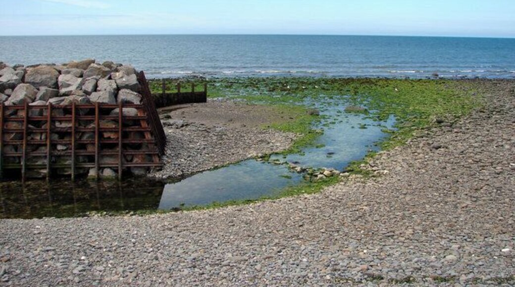 A rocky shoreline with a pile of rocks and a small water channel.