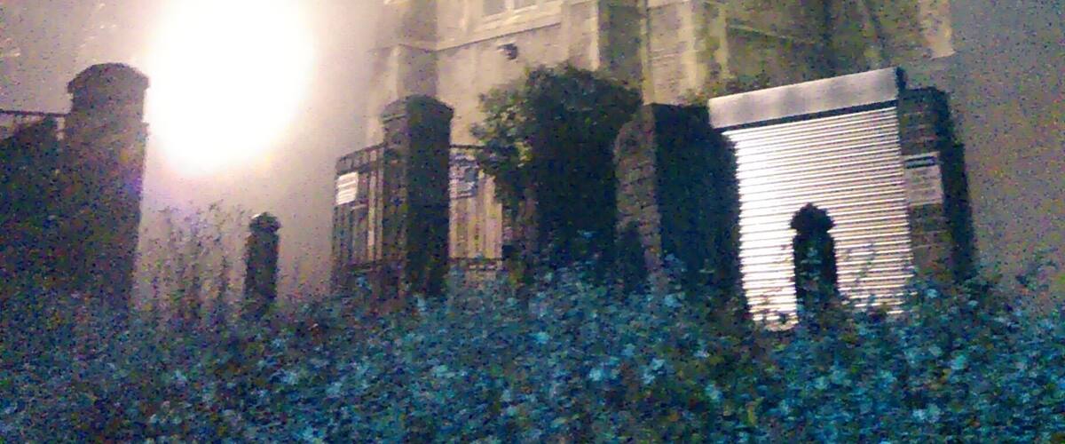 Un'alta chiesa con una torre dell'orologio illuminata da una luce intensa, di notte.