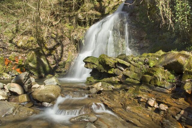 Una cascada que se precipita sobre rocas en un área boscosa.