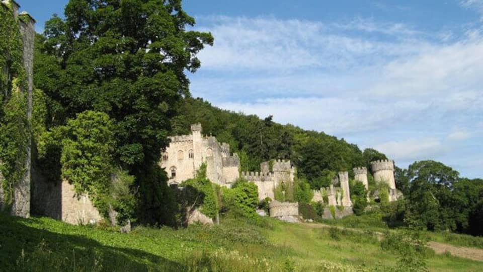 A historic castle surrounded by lush greenery and trees.