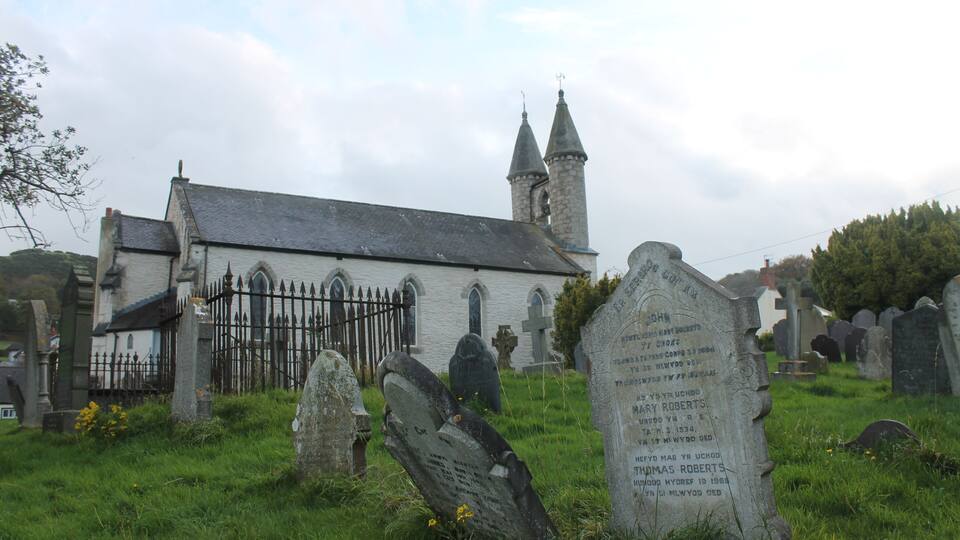 A church with a steeple and a graveyard with headstones.