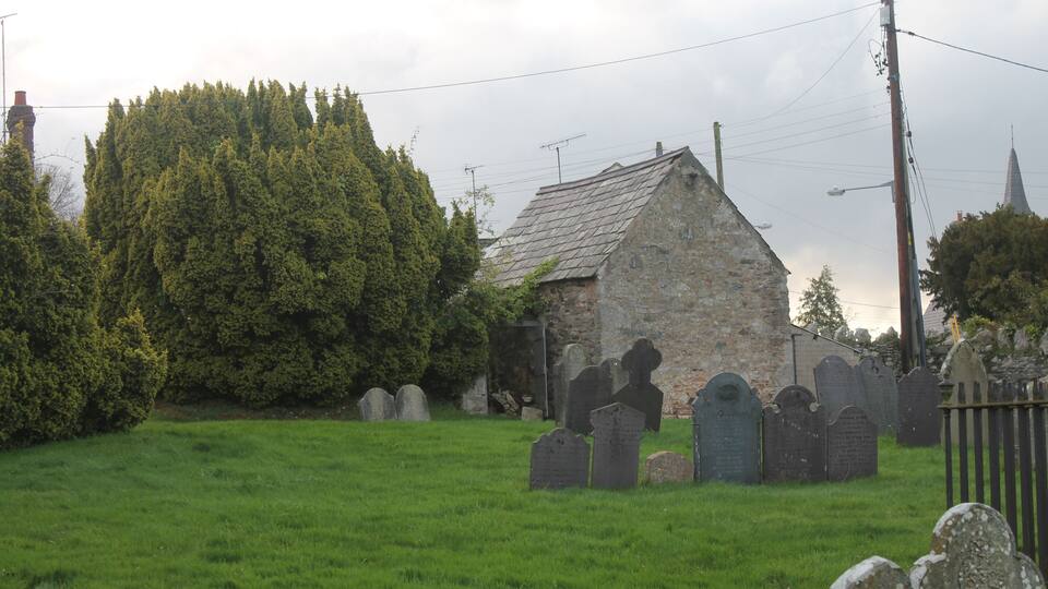 A cemetery with stone headstones and a stone church.