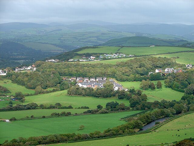 A rural landscape with rolling hills, a river, and scattered houses.