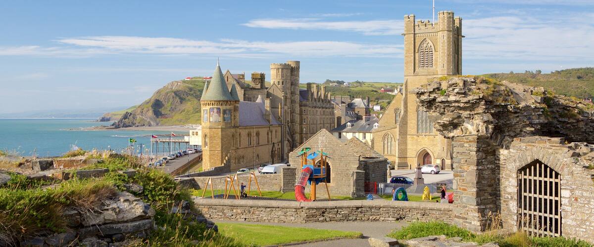 A historic castle with towers and a church, overlooking a coastal area with a clear sky.