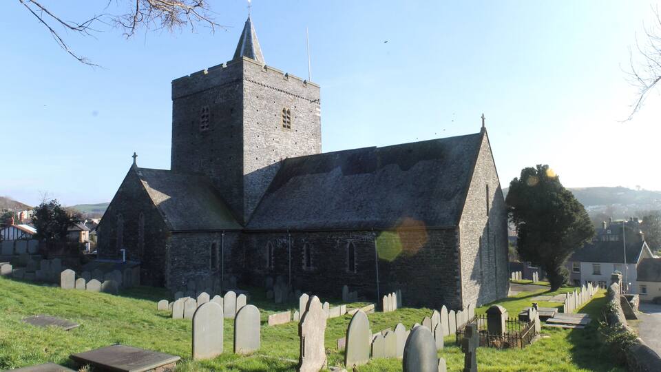 A church with a tall tower and a cemetery in the foreground.