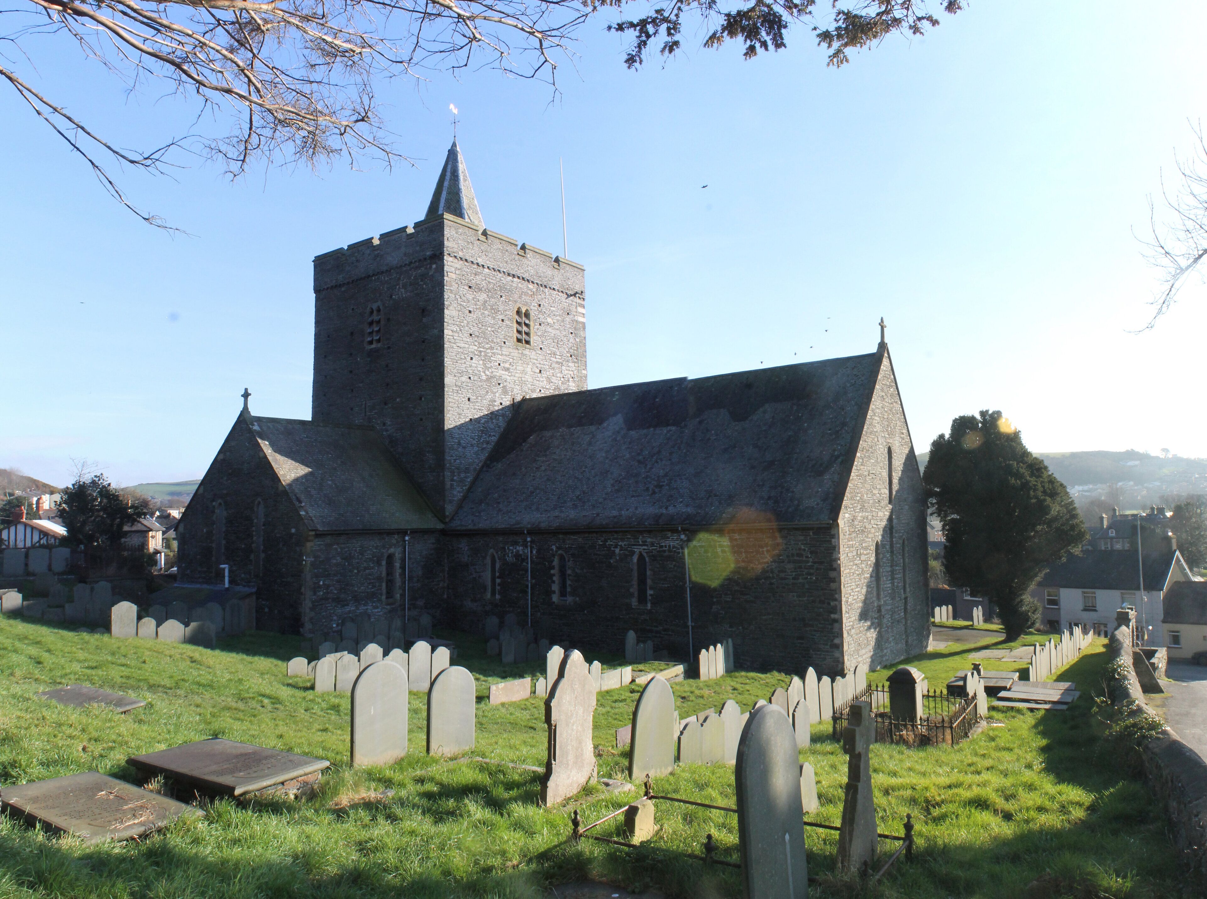 A church with a tall tower and a cemetery in the foreground.