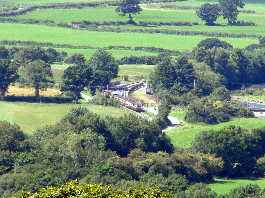 A Vale of Rheidol Railway train enters Capel Bangor station, Data from Geograph: Description: An up train (to Aberystwyth) enters Capel Bangor station, viewed from the top of the Pant Da Nature Reserve, about 1 mile away. The Vale of Rheidol Light Railway https://www.geograph.org.uk/gallery/the_vale_of_rheidol_light_railway_6996 ICBM: 52.399460433796, -3.9888929307688 Location: (about 1 km from) near to Capel Bangor, Ceredigion/Sir Ceredigion, Great Britain.