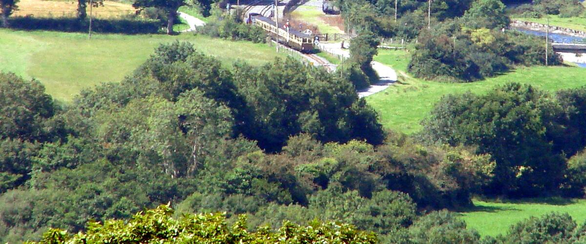 A railway bridge in a rural landscape with rolling green fields and scattered trees.