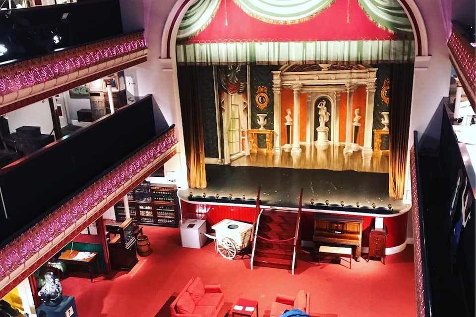 A theater with a red carpet, multiple levels, and ornate stage curtains.