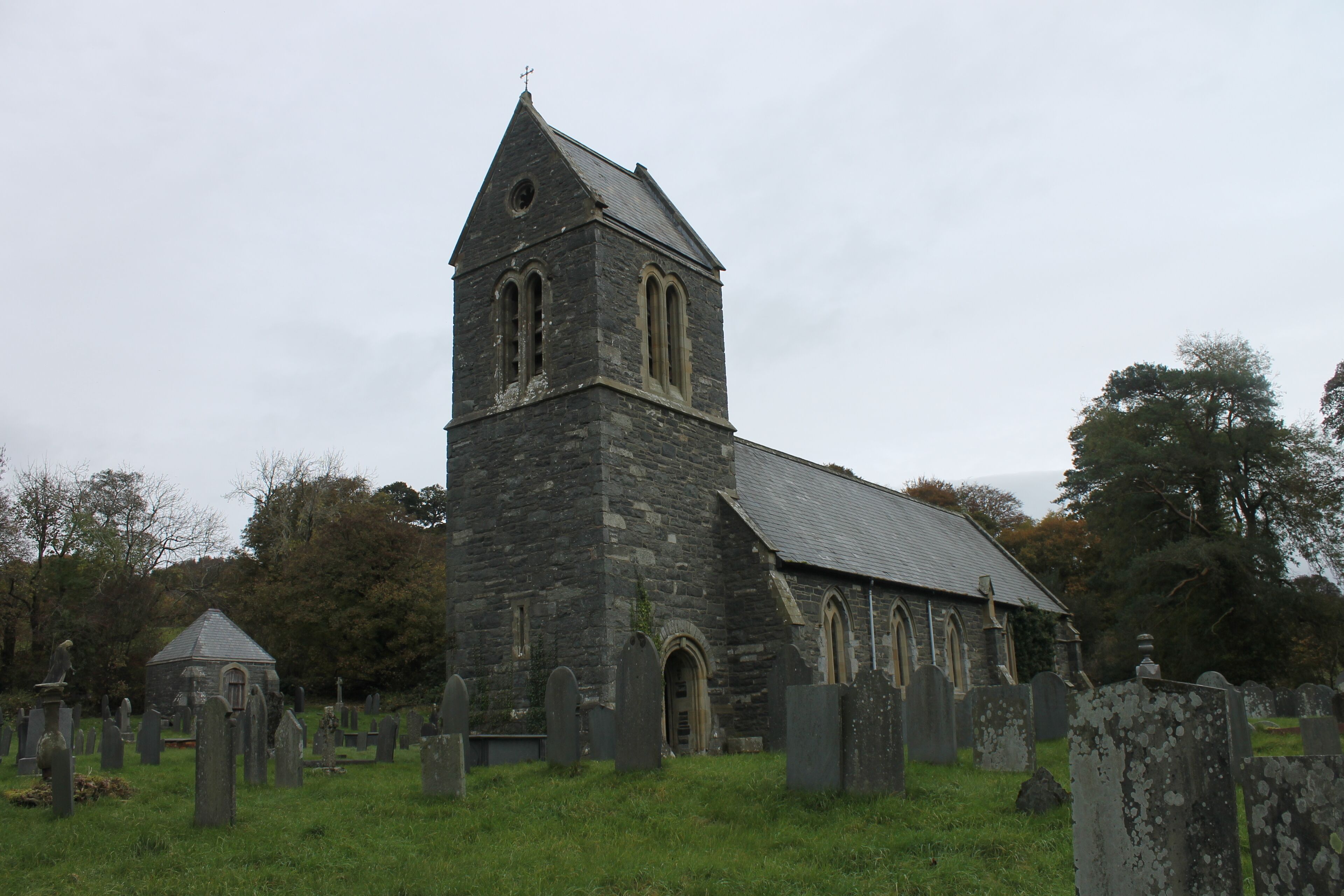 A stone church with a bell tower and a graveyard.