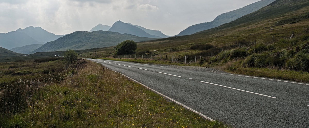 A rural road with mountains in the background.
