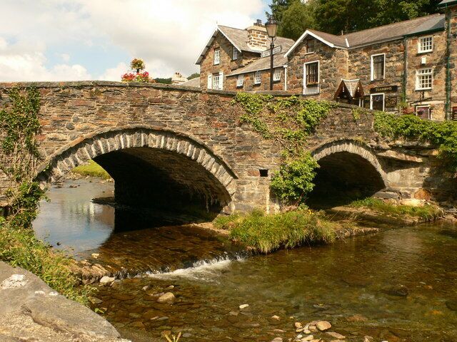 A stone bridge over a river with buildings on the right.