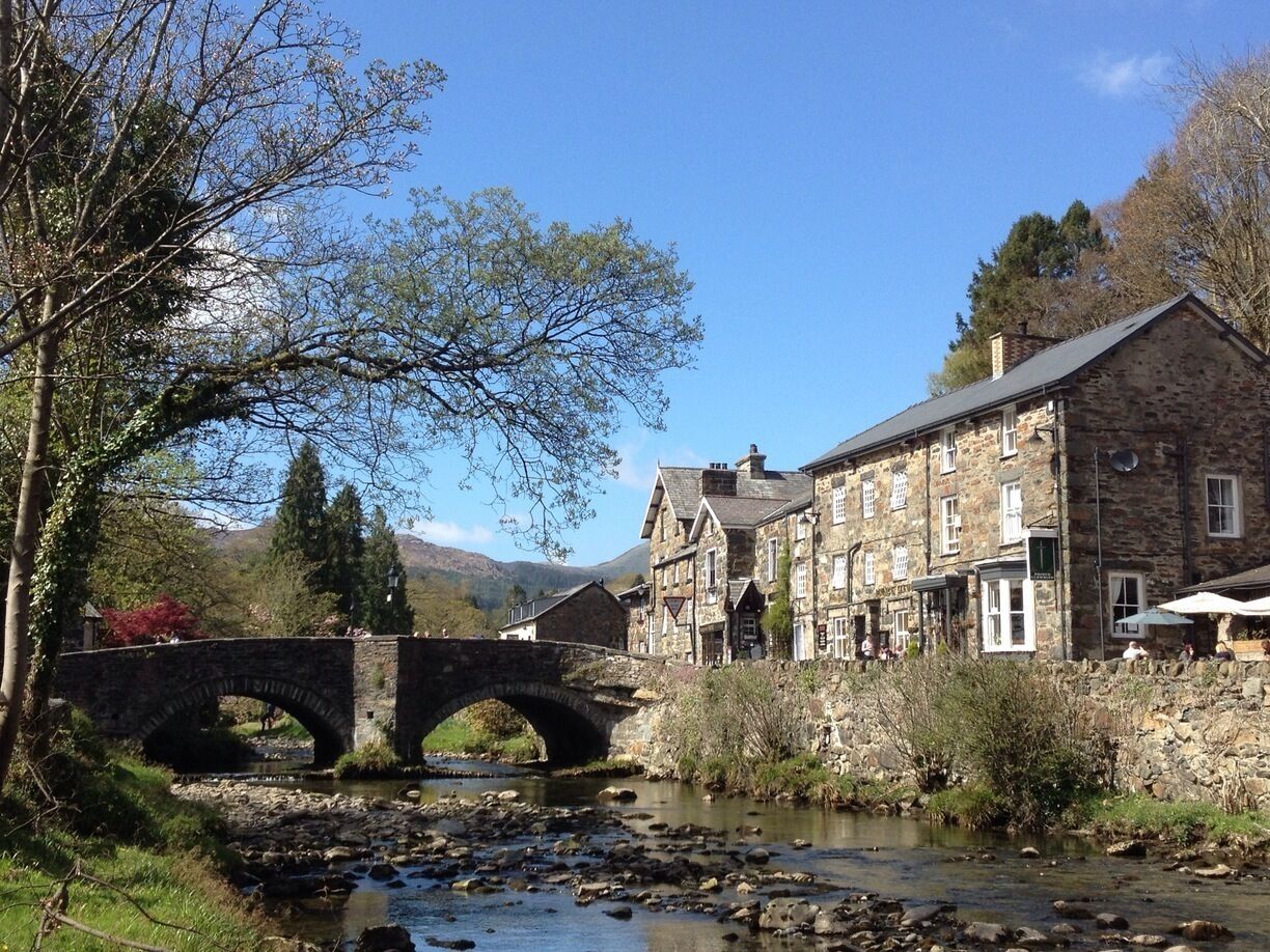 A stone bridge over a river, surrounded by stone buildings and trees.