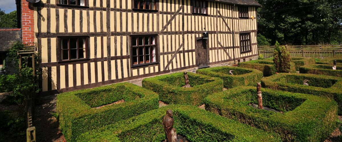 A Tudor-style half-timbered house with a well-maintained garden and hedges.