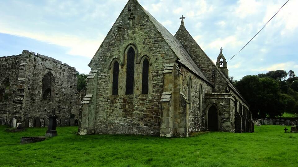 An old stone church with a steep roof and a bell tower.