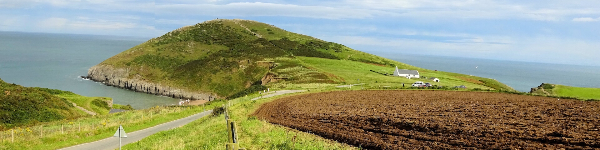Un paisaje costero con una colina, una carretera y un edificio blanco.