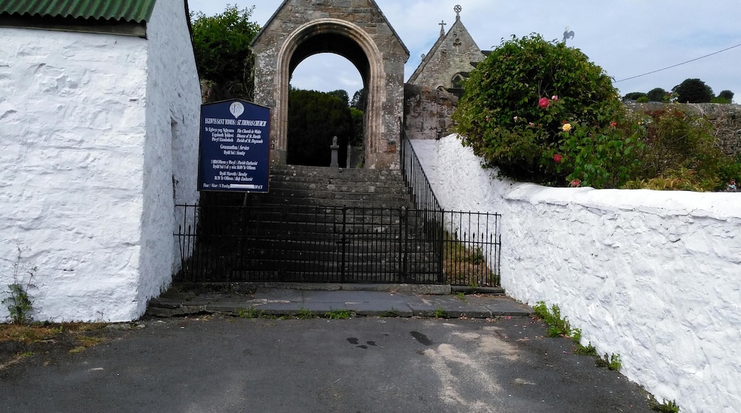 A stone archway leading to a church with a cross on top.
